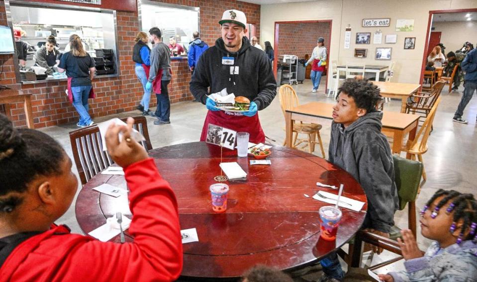 Volunteers serve guests no-cost meals in a restaurant-style setting at the new Papa Mike’s Café which opened officially with a ribbon cutting at the Poverello House on Wednesday, Jan. 24, 2024.