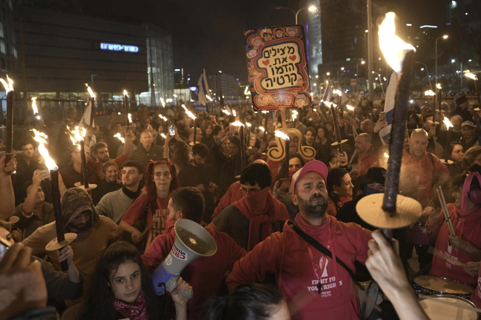 Israelis carry torches at a protest against Israeli Prime Minister Benjamin Netanyahu and his his far-right government that his opponents say threaten democracy and freedoms, in Tel Aviv, Israel, Saturday, Jan. 21, 2023. (AP Photo/ Oded Balilty)