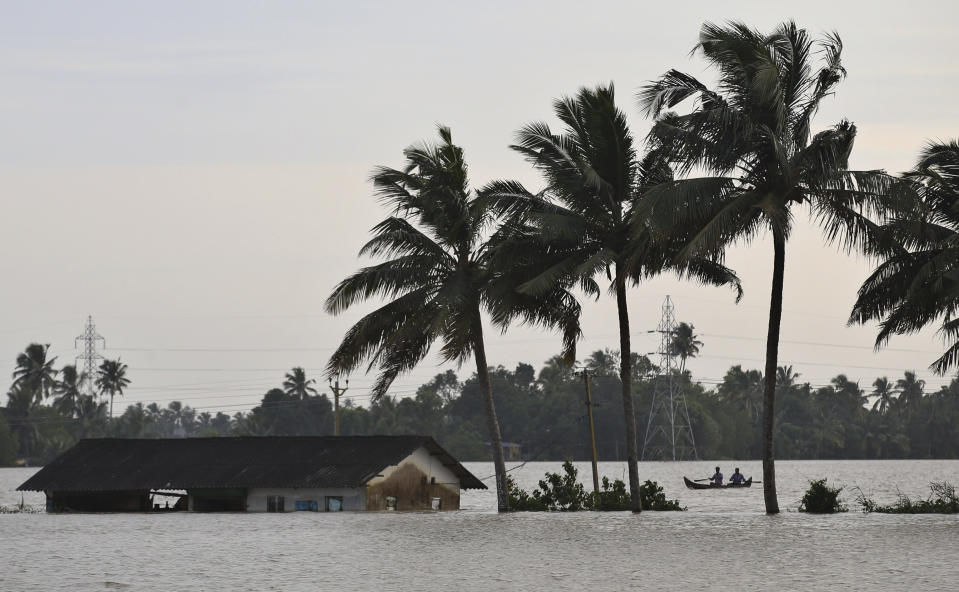 Two men row a boat through a flooded paddy field