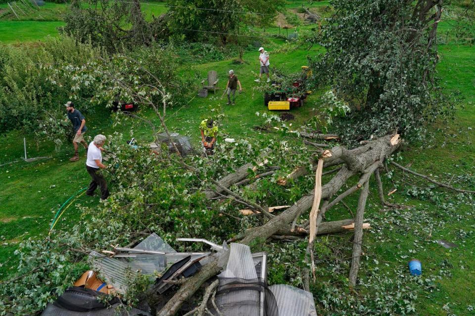 Dan Lietzau, of Brighton, center, uses a chainsaw to cut branches off a fallen tree in a woman’s yard on Noble Road in Williamston on Friday, Aug. 25, 2023, after a tornado touched down nearby, causing damage to the area.