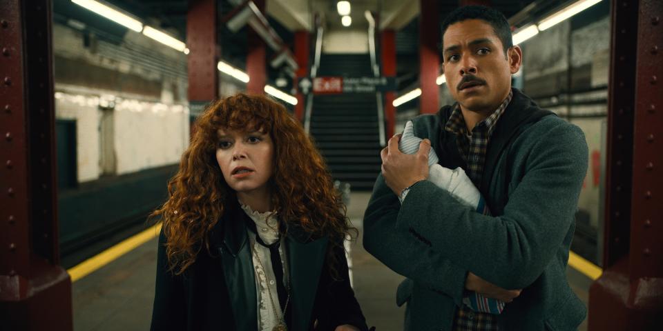 Nadia standing next to a man holding a baby on a subway platform in a scene from "Russian Doll"