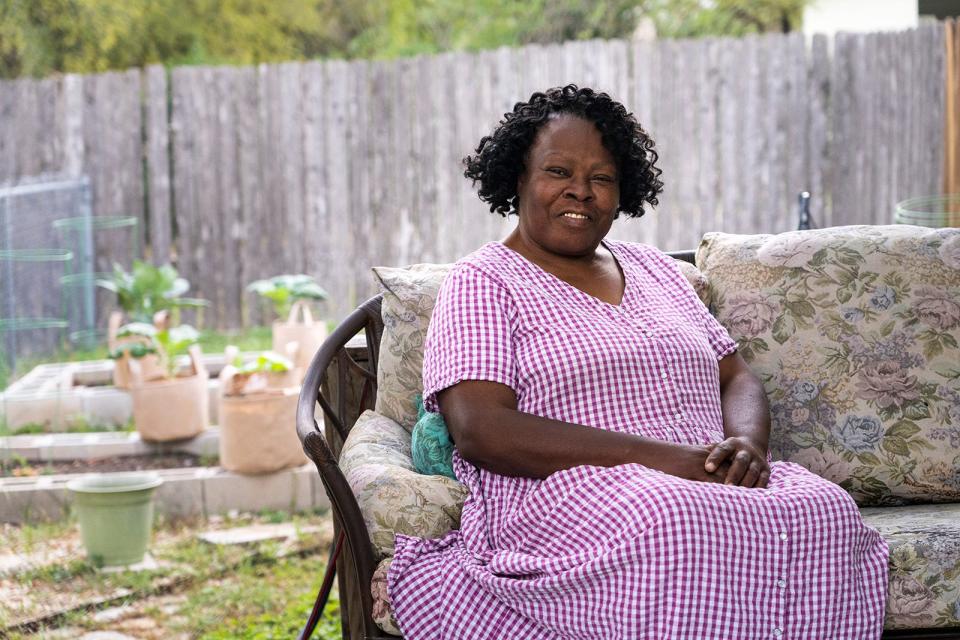 Sandra Stephenson relaxes on the back porch of her East Austin home. The backyard needs to be redone, as does a lot of the interior of the home.