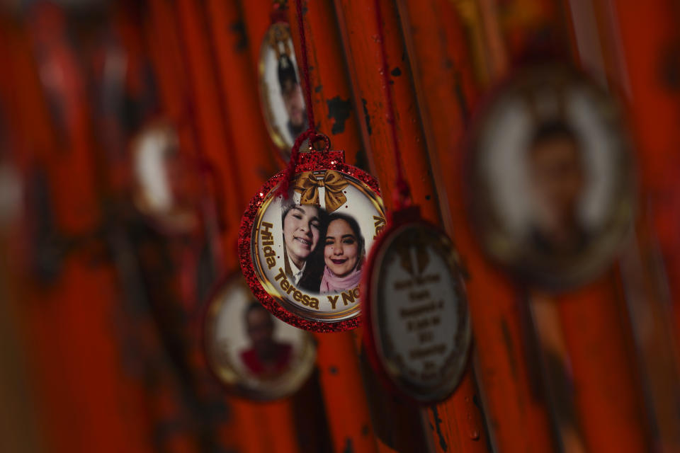 Ornaments hang from a crowd control barrier during a "posada", a traditional Christmastime procession, held in honor of missing relatives, in front of the National Palace in Mexico City, Dec. 22, 2023. Family members were asked to bring Christmas tree ornaments featuring the face of a disappeared person and a piñata to symbolize an obstacle they want to overcome. (AP Photo/Marco Ugarte)