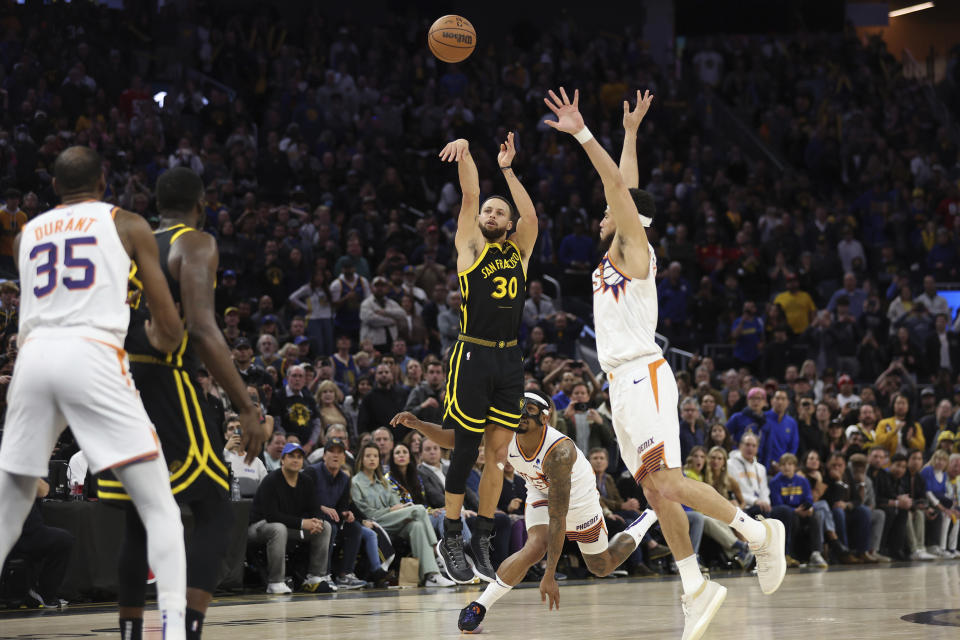 Golden State Warriors guard Stephen Curry (30) shoots a go-ahead basket against Phoenix Suns guards Devin Booker, right, and Bradley Beal, back center, during the second half of an NBA basketball game in San Francisco, Saturday, Feb. 10, 2024. (AP Photo/Jed Jacobsohn)