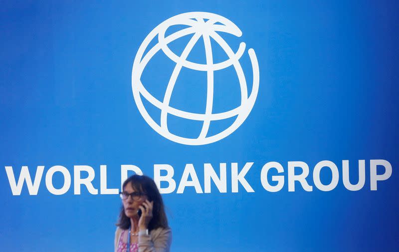 A participant stands near a logo of the World Bank at the International Monetary Fund - World Bank Annual Meeting 2018 in Nusa Dua