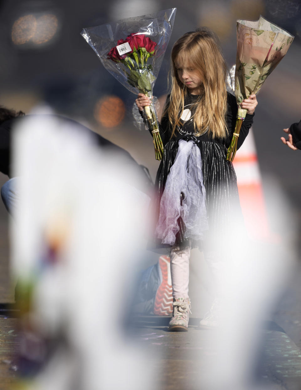 Six-year-old Harper Halvorson carries bouquets of flowers to place a makeshift memorial for victims of a weekend mass shooting at a nearby gay nightclub on Tuesday, Nov. 22, 2022, in Colorado Springs, Colo. Anderson Lee Aldrich opened fire at Club Q, in which five people were killed and others suffered gunshot wounds before patrons tackled and beat the suspect into submission. (AP Photo/David Zalubowski)