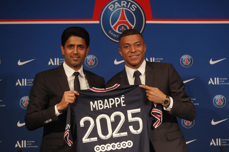 Kylian Mbappé (derecha) posa con su camiseta del Paris Saint-Germain junto al presidente Nasser Al-Khelaifi durante una rueda de prensa, el lunes 23 de mayo de 2022. (AP Foto/Michel Spingler)