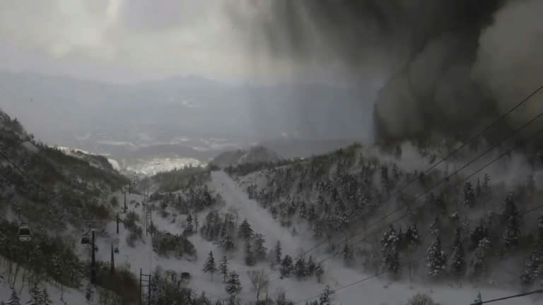 Thick black smoke rolling down the snow-covered side of Japan's Mt. Kusatsu Shirane towards a ski slope after a volcanic eruption