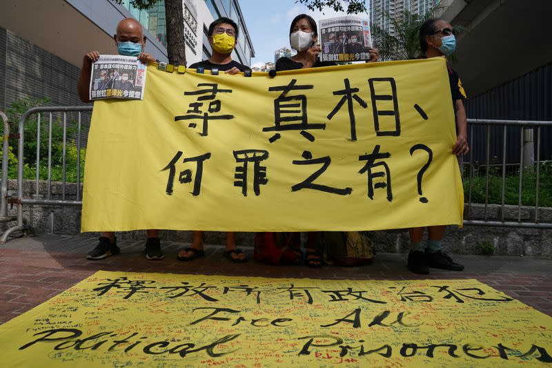 Supporters hold a copies of Apple Daily newspaper and a banner during a court hearing outside West Magistrates’ Courts, after police charge two executives of the pro-democracy Apple Daily newspaper over the national security law, in Hong Kong