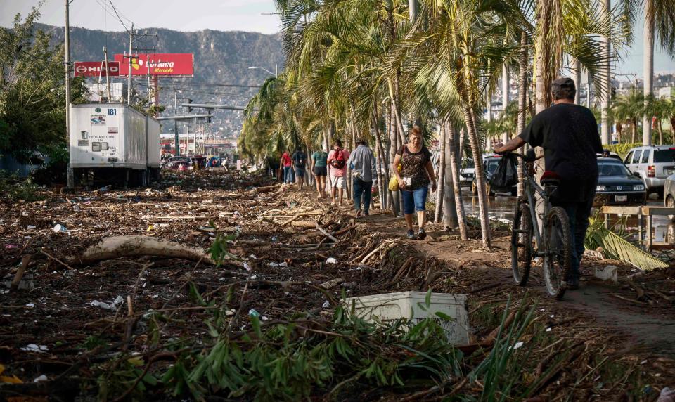 People walk next to debris left after the passage of Hurricane Otis in Acapulco (AFP via Getty Images)