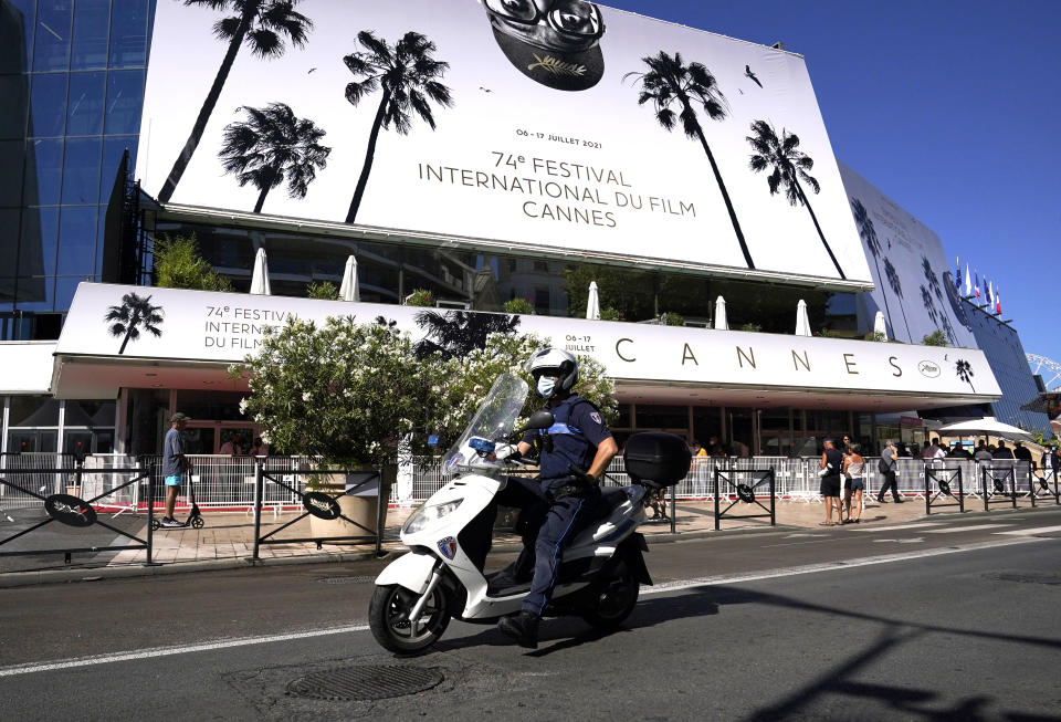 A police officer rides a scooter whilst passing the Palais des during preparations for the 74th international film festival, Cannes, southern France, July 5, 2021. The Cannes film festival runs from July 6 - July 17, 2021. (AP Photo/ Brynn Anderson)