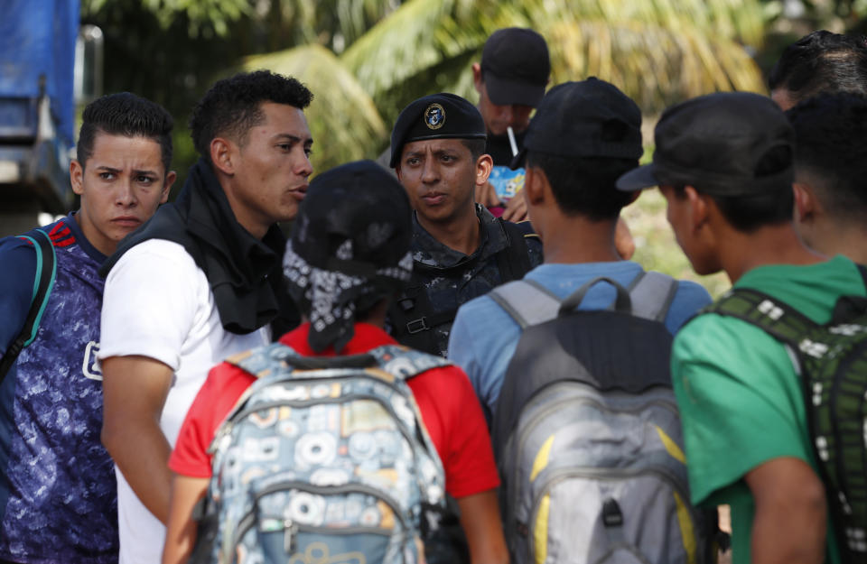 A Guatemalan police officer stops Honduran migrants trying to reach the United States who crossed the Honduran border, in Morales, Guatemala, Wednesday, Jan. 15, 2020. Migrants in the group said they left Honduras very late Tuesday, around midnight. (AP Photo/Moises Castillo)