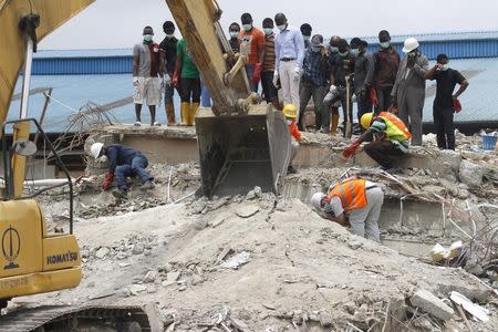 Rescue workers search for victims under a concrete floor as an excavator removes rubble at the site of the collapsed Synagogue Church of All Nations in the Ikotun-Egbe neighbourhood of Nigeria's commercial capital Lagos, September 17, 2014. REUTERS/Akintunde Akinleye