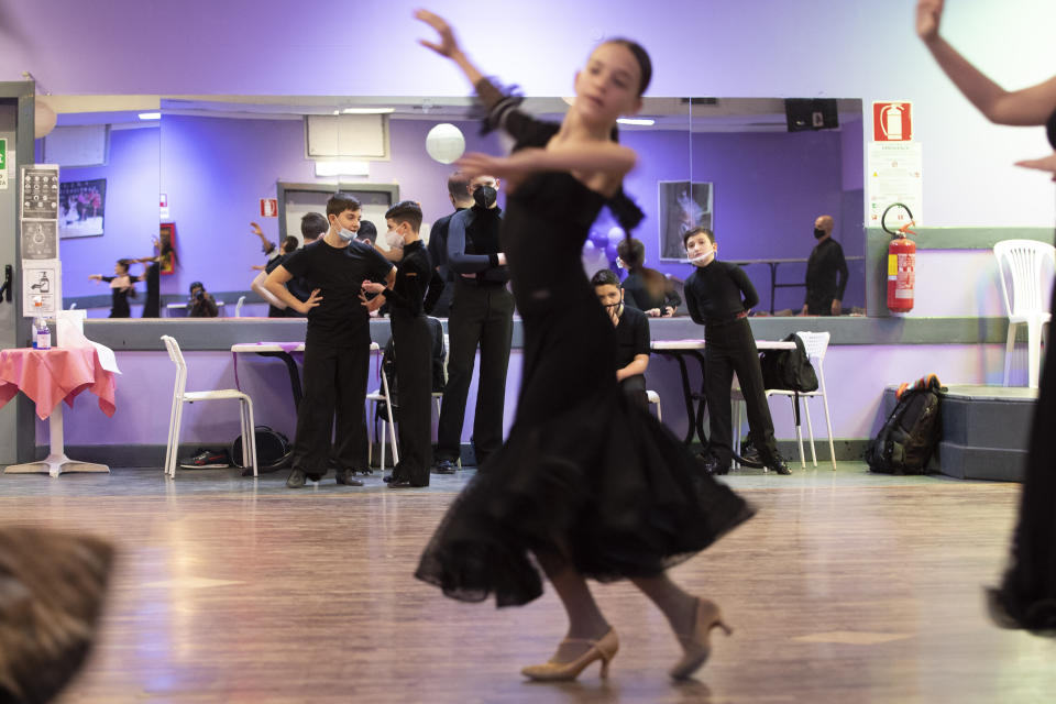 Dancers, wearing face masks to curb the spread of COVID-19 look at their schoolmates training at the New Dancing Days school, in Rome, Wednesday, March 24, 2021. While much of Italy is in coronavirus lockdown, with live music and theatrical performances barred, cinemas shuttered and many sporting activities limited, competitive ballroom dancing is alive and well here, albeit with precautions. (AP Photo/Alessandra Tarantino)