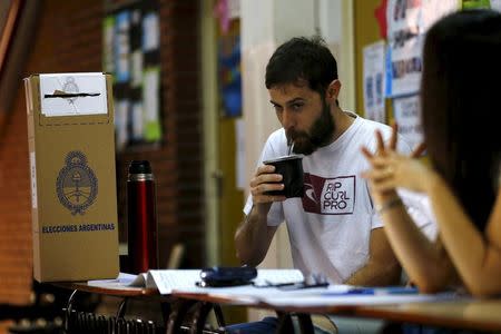 An election officer drinks a "mate", a traditional herbal infusion, as they wait for citizens to arrive to vote for the presidential election at Buenos Aires, Argentina, November 22, 2015. REUTERS/Ivan Alvarado