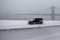 A jeep makes its way north though heavy snow on the FDR Drive with the Brooklyn Bridge in background during a snowstorm in the Manhattan borough of New York, January 23, 2016. REUTERS/Carlo Allegri