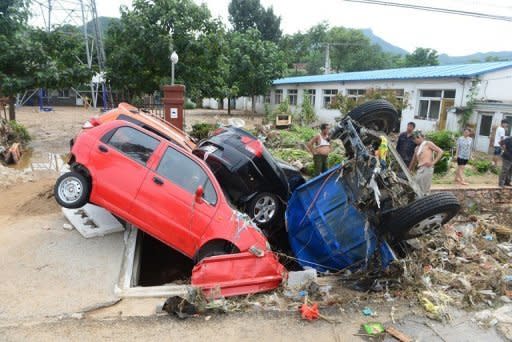 Chinese workers try to clear up damaged cars and debris after heavy rains in Beijing on July 23. The death toll from the worst rains to hit Beijing in more than 60 years has risen to 77 -- more than double the previous figure, according to the Xinhua news agency