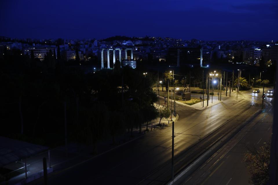 In this Thursday, April 2, 2020 photo, a few cars use the empty Amalias avenue with the temple of Zeus in the background, in central Athens during the lockdown. Deserted squares, padlocked parks, empty avenues where cars were once jammed bumper-to-bumper in heavy traffic. The Greek capital, like so many cities across the world, has seen its streets empty as part of a lockdown designed to stem the spread of the new coronavirus. (AP Photo/Thanassis Stavrakis)