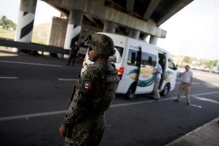 A military police officer observes traffic at an immigration checkpoint on a road in Tapachula