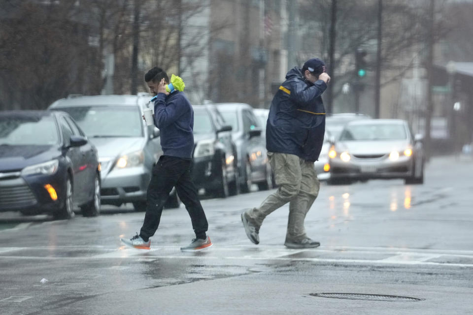 Passers-by are buffeted by wind as they cross a street, Monday, Dec. 18, 2023, in Boston. A storm moving up the East Coast brought heavy rain and high winds to the Northeast on Monday, threatening flooding, knocking out power to hundreds of thousands. (AP Photo/Steven Senne)