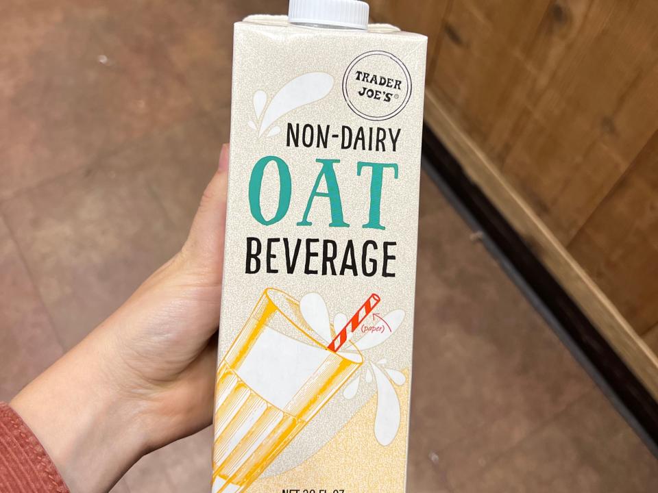 The writer holds a carton of Trader Joe's non-dairy oat beverage