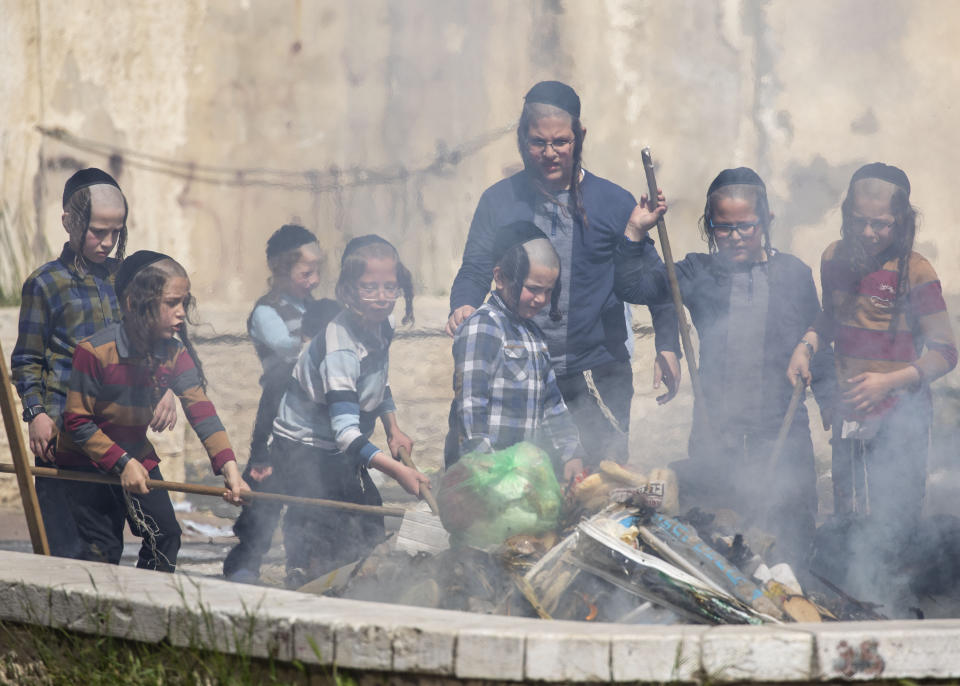 Ultra-Orthodox Jewish children burn leavened items in final preparation for the Passover holiday in the Orthodox neighborhood of Mea Shearim in Jerusalem, Wednesday, April 8, 2020. Jerusalem authorities have said they will gather the bread and burn it in a big bonfire in one location to avoid large gatherings. But, some in the Mea Shearim neighbourhood shunned the orders. Many of Israel's ultra-Orthodox residents, obeying their religious leaders, have ignored pleas to stay home in the face of the coronavirus threat. (AP Photo/Ariel Schalit)