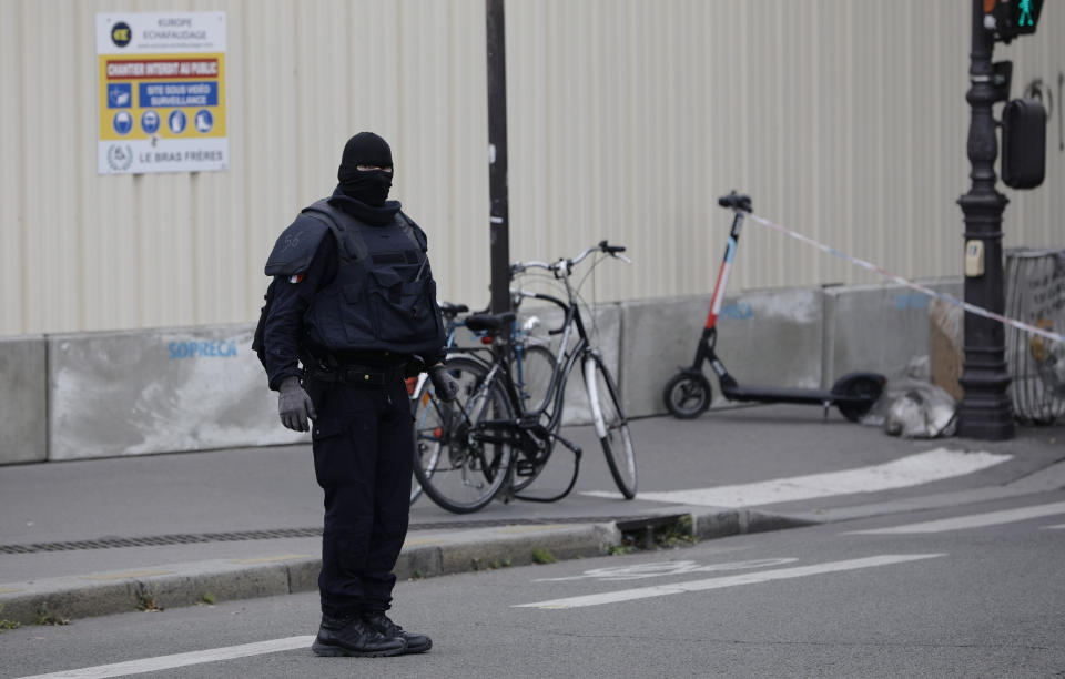 A masked police officer stands next to a police tape after an incident in Paris, Thursday, Oct. 3, 2019. A French police union official says an attacker armed with a knife has killed one officer inside Paris police headquarters before he was shot and killed. (AP Photo/Kamil Zihnioglu)