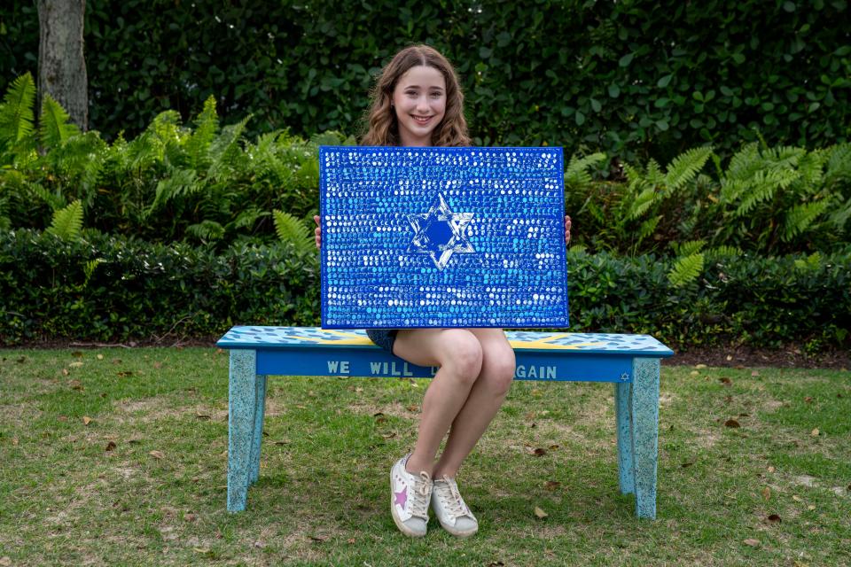 Ayel Morgenstern, 13, holds her "Little Finger of God" painting and sits on her Sunny Seat bench in Boca Raton.