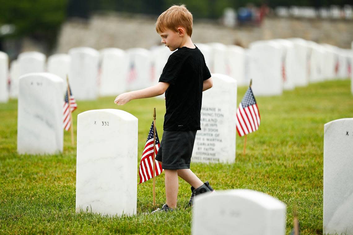 Draven Wright, 7, of Nicholasville, Ky., places coins on headstones before a Memorial Day ceremony at Camp Nelson National Cemetery in 2019.