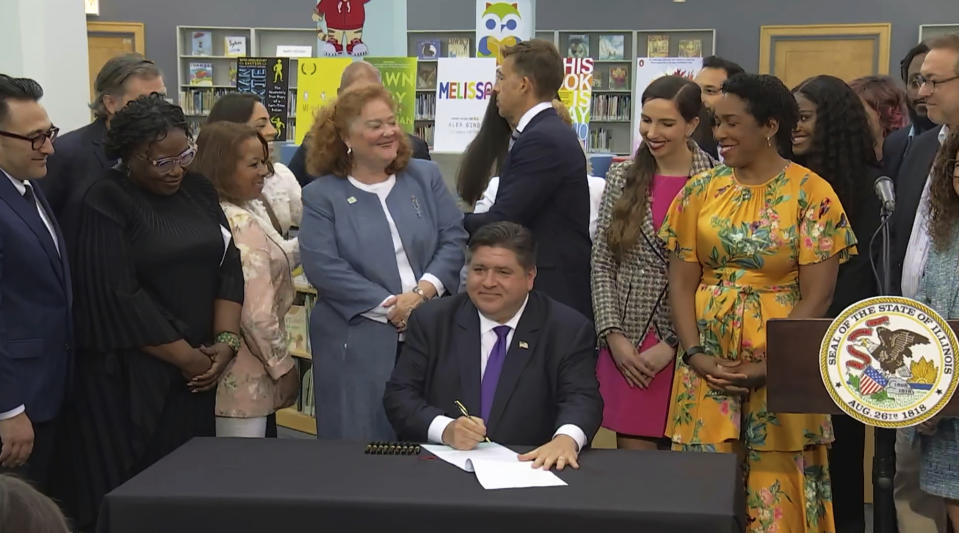 FILE - In this screenshot from a livestream broadcast by the State of Illinois, Gov. J.B. Pritzker signs a bill, June 12, 2023, at Harold Washington Library's Thomas Hughes Children's Library in downtown Chicago. The law will require the state's libraries to uphold a pledge not to ban material because of partisan disapproval, starting Monday, Jan. 1, 2024. If they refuse, they will not receive state funding. (State of Illinois via AP, File)