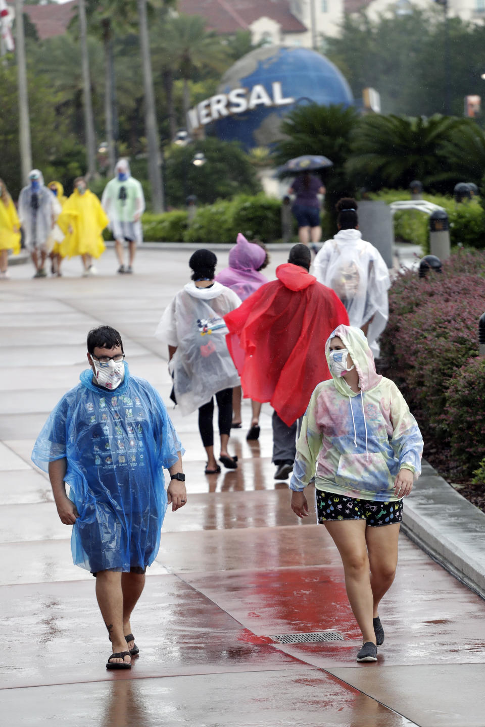 Visitantes bajo la lluvia en Universal Studios, el miércoles 3 de junio de 2020 en Orlando, Florida. El parque temático reabrió sus puertas para aquellos con pases de temporada y abrirá al público general el viernes. (AP Foto/John Raoux)