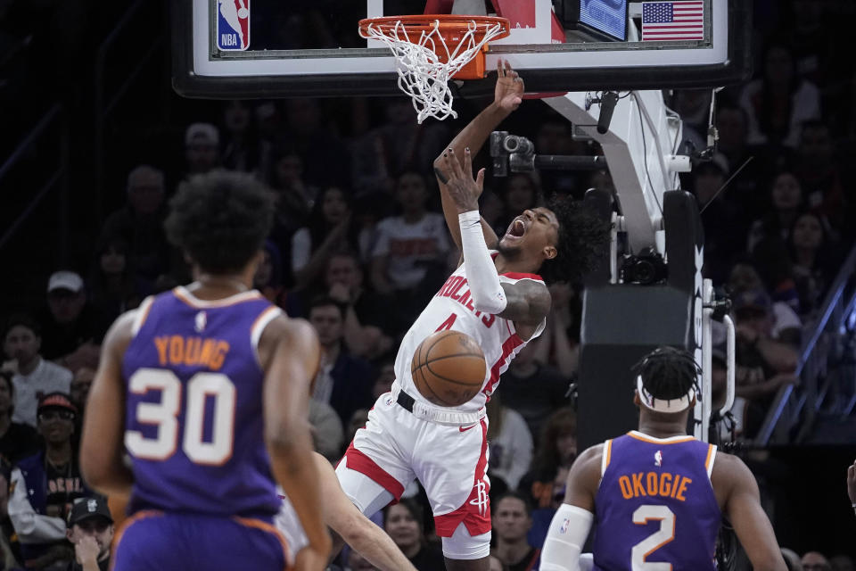 Houston Rockets guard Jalen Green, center, celebrates after a dunk between Phoenix Suns forwards Thaddeus Young (30) and Josh Okogie (2) during the second half of an NBA basketball game in Phoenix, Saturday, March. 2, 2024. (AP Photo/Darryl Webb)