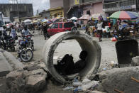 A man uses his cellphone inside a concrete pipe at a market in Cap-Haitien, Haiti, Thursday, July 22, 2021. The city of Cap-Haitien is holding events to honor slain President Jovenel Moïse on Thursday ahead of Friday’s funeral. (AP Photo/Matias Delacroix)