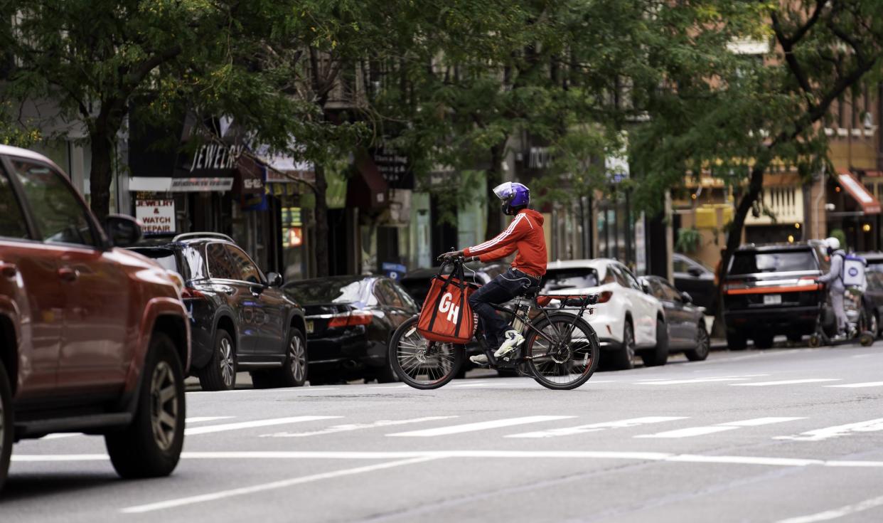 New York, NY, USA - September 29, 2021: A Grubhub delivery man crosses Third Avenue at East 88th Street on Manhattan's upper east side just before the light changes and the Third Avenue traffic flows north.