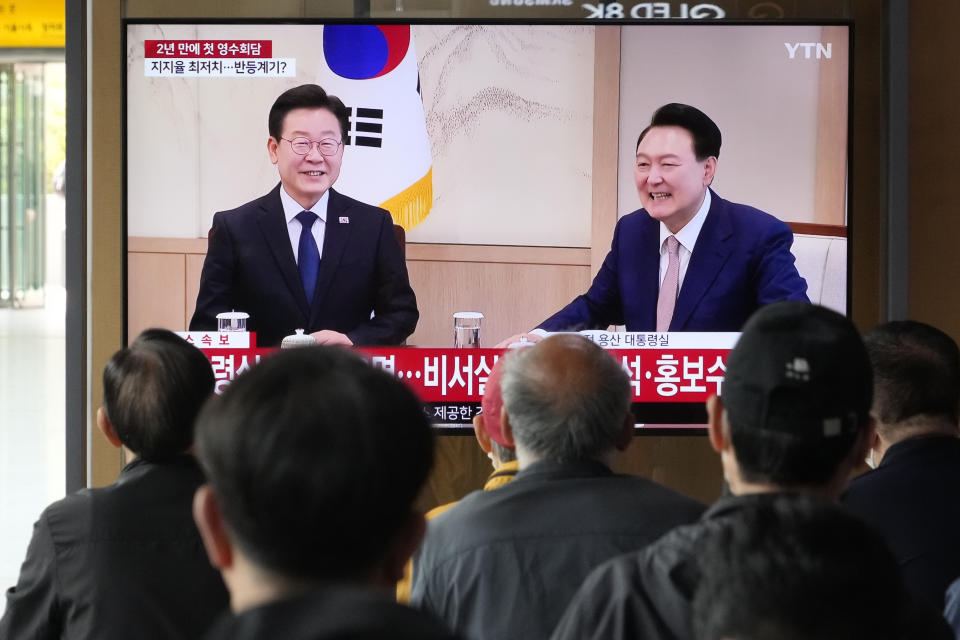 People watch a TV screen showing South Korean President Yoon Suk Yeol, right, meeting with main opposition Democratic Party leader Lee Jae-myung, during a news program at the Seoul Railway Station in Seoul, South Korea, Monday, April 29, 2024. (AP Photo/Ahn Young-joon)