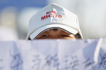 A family member of a passenger onboard Malaysia Airlines flight MH370 which went missing in 2014 holds a banner during a gathering in front of the Malaysian Embassy on the second anniversary of the disappearance of MH370, in Beijing, China, March 8, 2016. REUTERS/Damir Sagolj