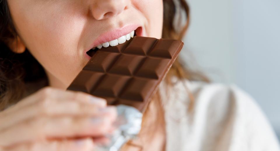 Woman bites through a block of chocolate. (Getty Images)