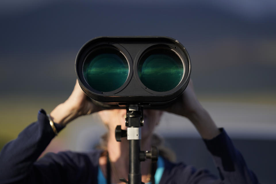 Janice Hazen of Ocean View, Hawaii, uses a binocular to view the Mauna Loa volcano as it erupts Wednesday, Nov. 30, 2022, near Hilo, Hawaii. (AP Photo/Gregory Bull)