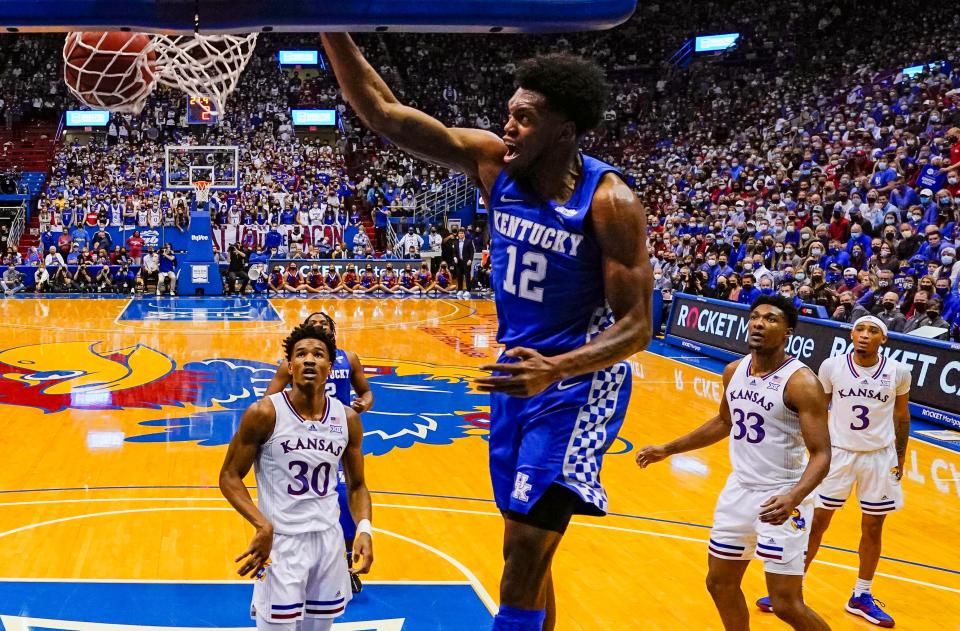 Kentucky Wildcats forward Keion Brooks Jr. (12) dunks the ball as Kansas Jayhawks guard Ochai Agbaji (30) and guard Dajuan Harris Jr. (3) look on during the first half at Allen Fieldhouse.