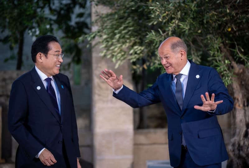 German Chancellor Olaf Scholz (R) speaks with Japanese Prime Minister Fumio Kishida at the family photo after the meeting of the G7 and outreach guests at the G7 summit. Michael Kappeler/dpa