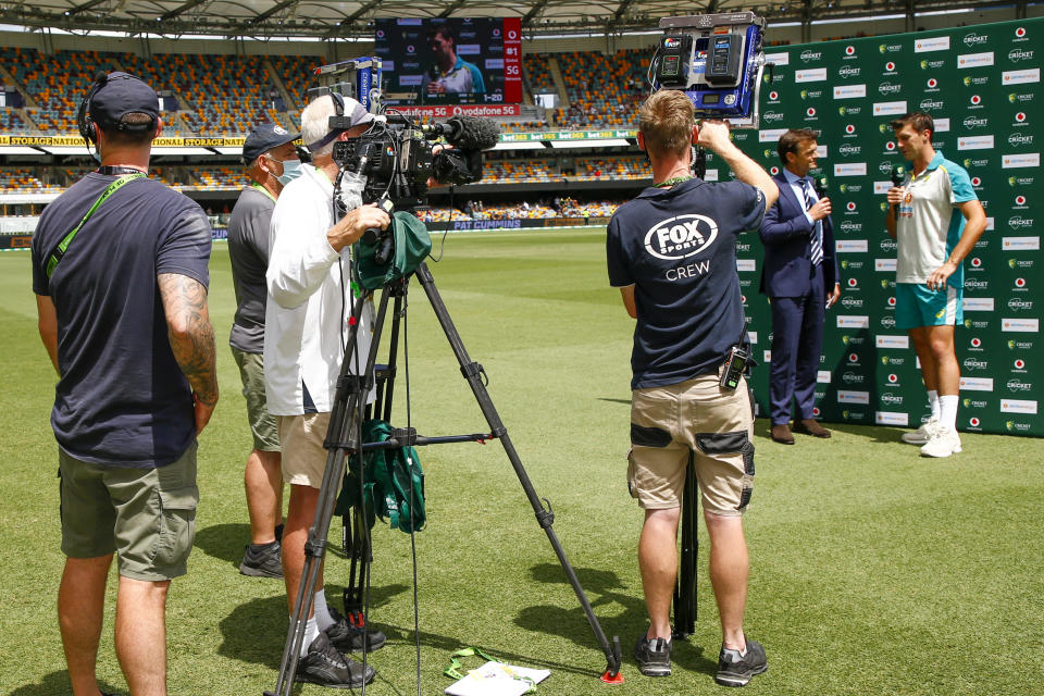 Television cameras film Australian captain Pat Cummins, right, as he is interviewed following play on day four of the first Ashes cricket test at the Gabba in Brisbane, Australia, Saturday, Dec. 11, 2021. A power outage at the broadcast compound cut the TV feed for at least 15 minutes on Saturday, and created another round of technology issues for the match officials.(AP Photo/Tertius Pickard)