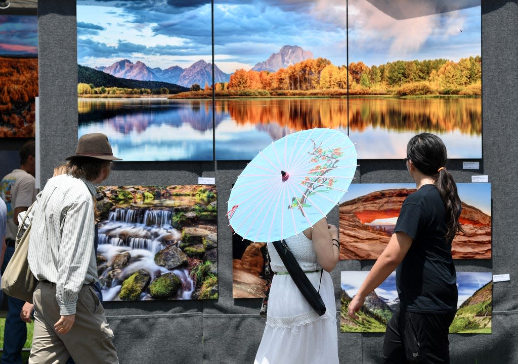 People look at the photography of Glenn Lewis printed on aluminum during the 48th Annual Mayfaire by-the-Lake in Lakeland, FL on Saturday May 11, 2019. The show continues from 9am to 4pm on Sunday.