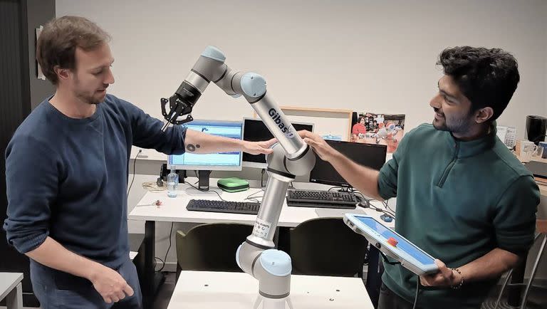 Pablo Lanillos, coordinador del proyecto Metatool, (a la izquierda) y el investigador postdoctoral Ajith Anil Meera trabajan con uno de sus robots industriales