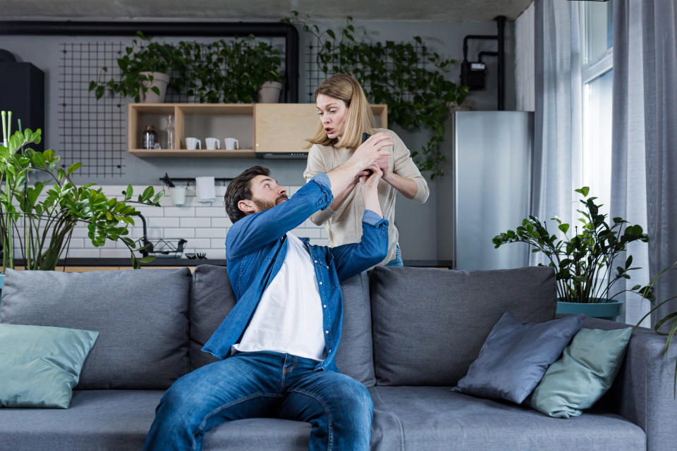 A man trying to grab his partner's phone out of her hands