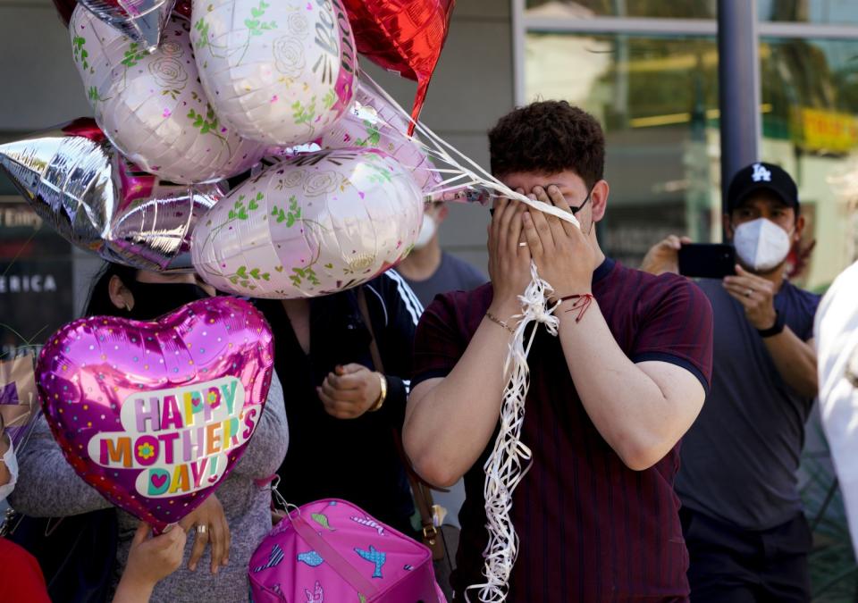 Bryan Chavez covers his tearful face after he and his mother reunite.