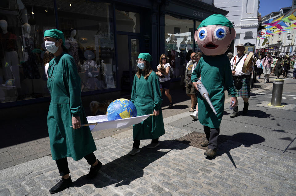 Activists dressed as medical personnel hold a giant syringe and a globe on a stretcher as they march through the streets during a demonstration around the meeting of the G7 in Falmouth, Cornwall, England, Saturday, June 12, 2021. Leaders of the G7 gather for a second day of meetings on Saturday, in which they will discuss COVID-19, climate, foreign policy and the economy. (AP Photo/Alberto Pezzali)