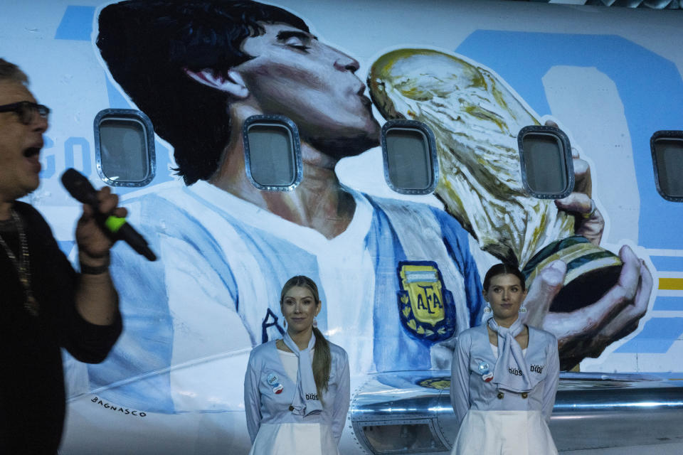 El cantante de rock Juanse actúa delante de dos sobrecargos durante la presentación de un avión dedicado al fallecido Diego Maradona, el miércoles 25 de mayo de 2022, en Buenos Aires (AP Foto/Rodrigo Abd)