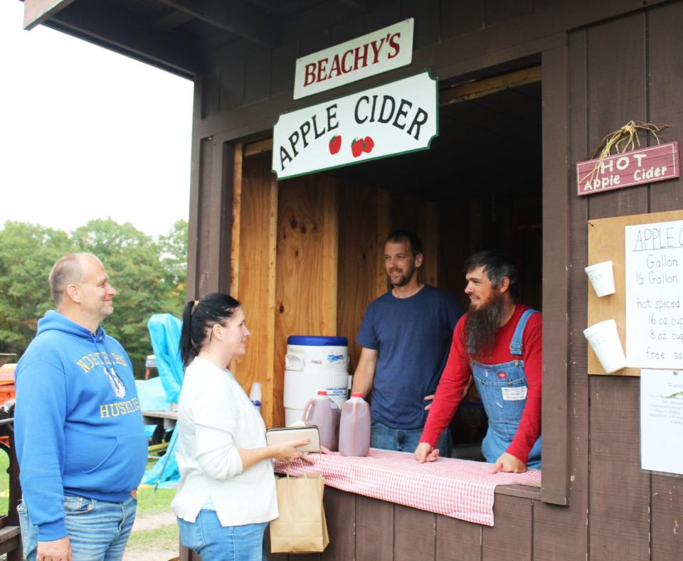 Scott and Sheri Sechler of Grantsville, Maryland, take some time to buy apple cider from Loren Yoder and Michael Petersheim during the 65th Springs Folk Fest on Friday.