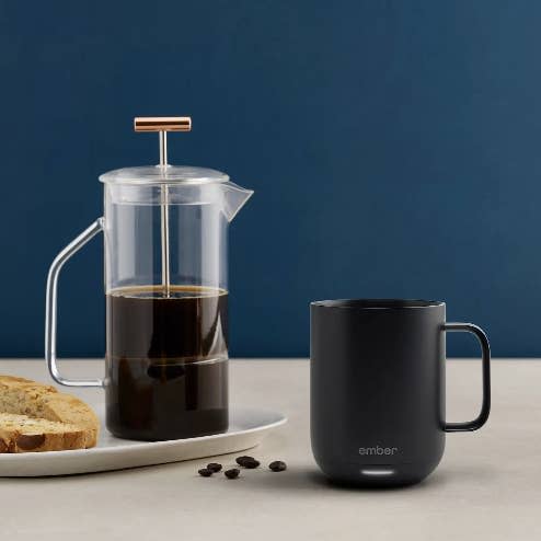 The black Ember mug next to a French press coffee machine