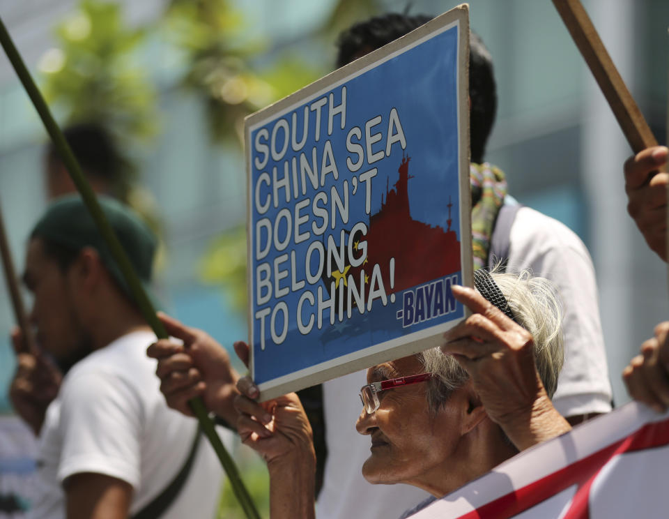 A Filipino woman protester holds a placard with slogans during a rally outside the Chinese consulate at the financial district of Makati, south of Manila, Philippines on Tuesday, April 22, 2014. The group is demanding an end to China's alleged incursions in the South China Sea and to press the Chinese government to respect the arbitral process under the United Nations Convention on the Law of the Sea. (AP Photo/Aaron Favila)